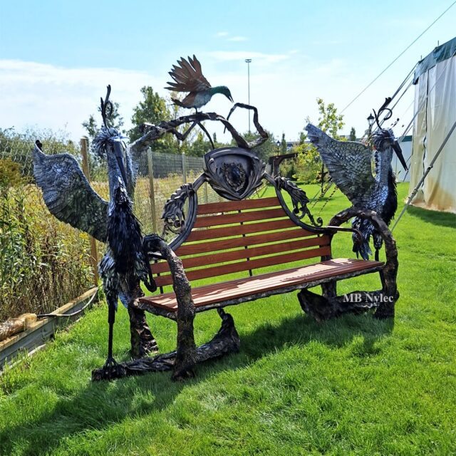 Blacksmith sculpture bench on a lawn in Warsaw