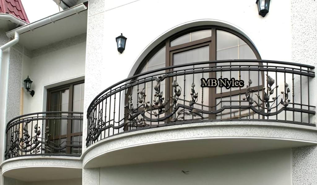 Traditional bowed balcony railing BWZ12 with vertical bars and forged leaves beneath a large arched window