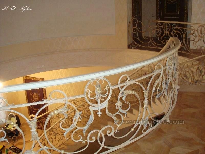 Cream hand-forged balustrade BA19 with a white handrail on a curved marble stair