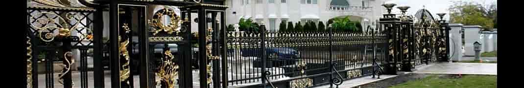 Black and gold wrought iron estate gates and fence at a luxury residence