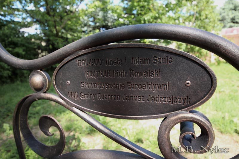Dedication plaque framed by a scrolled arm on the forged bench MK1C