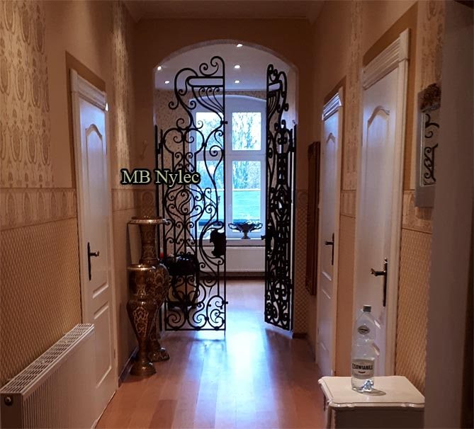 Double forged door grille DZ4 closing an arched passage at the end of a hallway