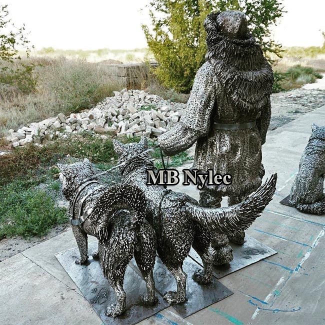 Steel sculpture Z87 of an Arctic traveller in a fur parka leading two husky dogs