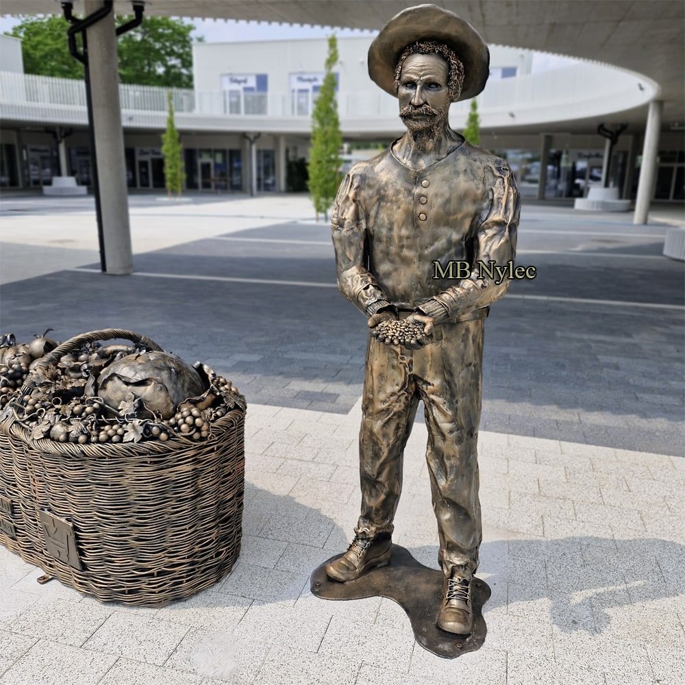 Farmer sculpture next to a steel fruit basket in Ciechanów