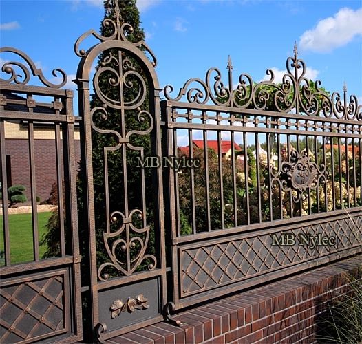 Slender forged fence pillar S4 with an arched top and leafy lower panel in fence BP54