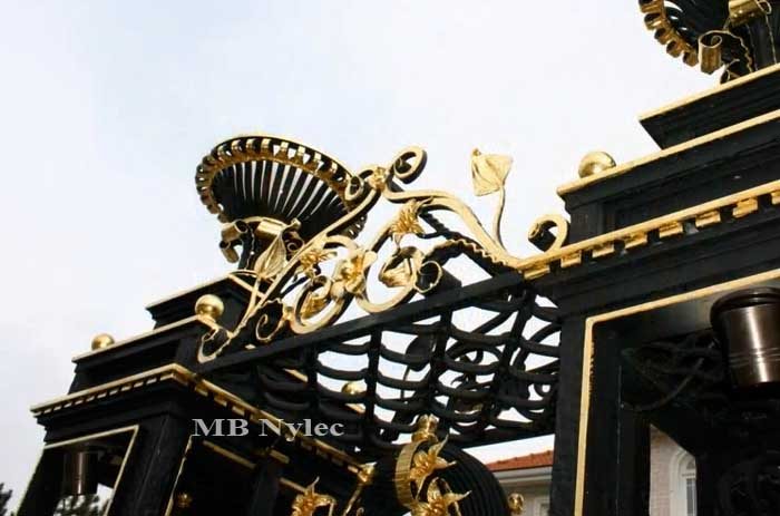 Forged crown with a gilded lily scroll over a wicket between S3 pillars
