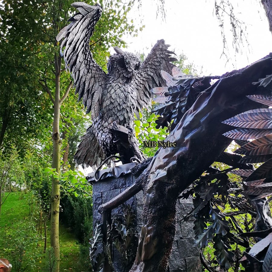 Eagle owl sculpture Z120 crowning a gate pillar beside forged tree branches