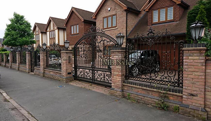 Forged fence BP234 with a matching arched driveway gate in front of brick houses