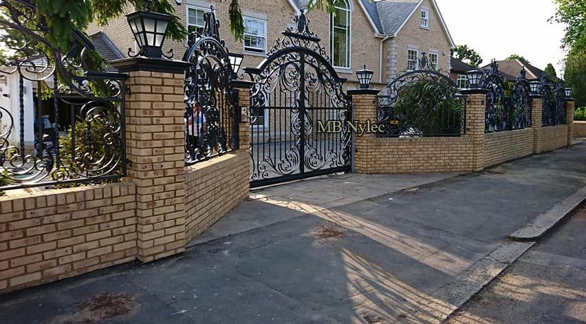 Forged fence BP235 and a matching arched gate in front of English-style brick houses
