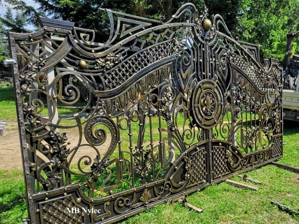 Forged gate leaf BP182 showing the bronze roundel and lattice wings in the workshop yard