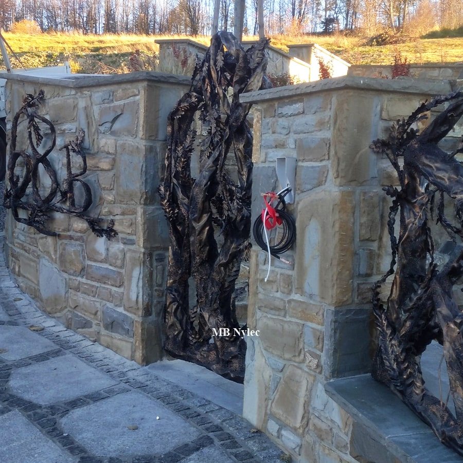 Forged tree wicket gate next to a matching sculpted fence panel