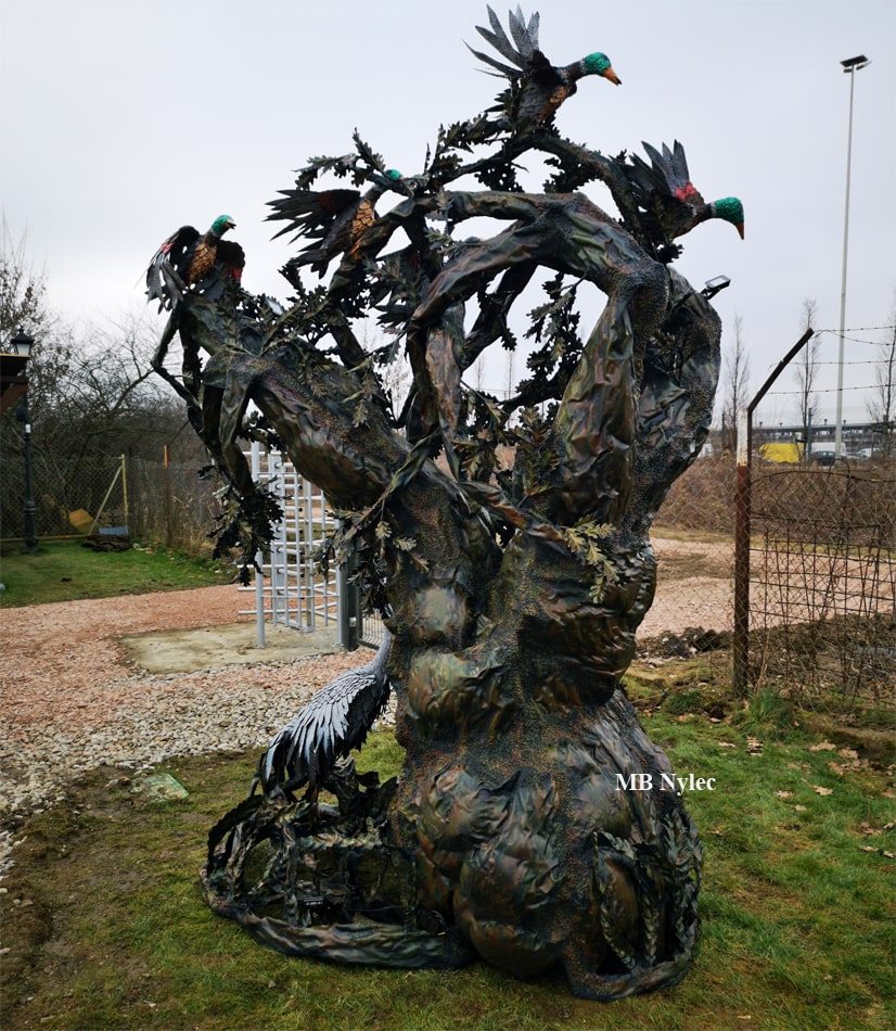 Side view of a forged steel tree lamp in a garden