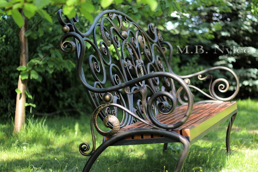 Side view of the bench MK1 on a lawn showing the curve of its arm