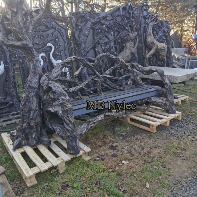 Garden bench with steel herons among forged branches