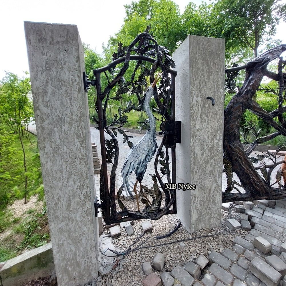 Steel garden gate with a heron sculpture between concrete pillars
