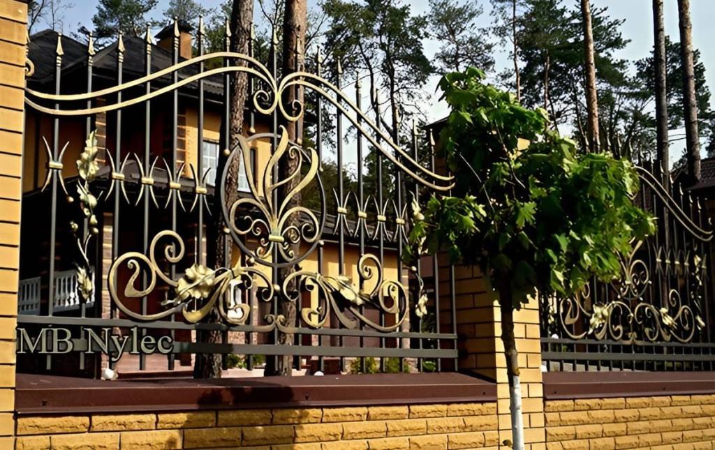 Wrought iron fence BP249 in graphite and gold with a central lily motif among pine trees