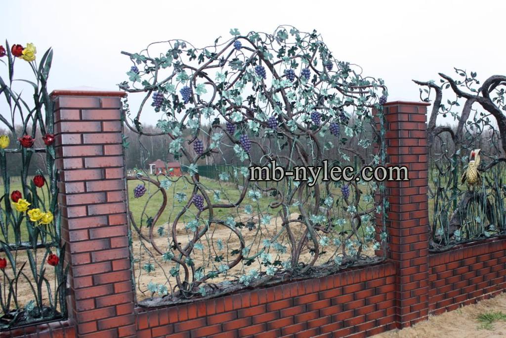 Forged steel fence span BM45 with a climbing grapevine, leaves and bunches of grapes between brick pillars