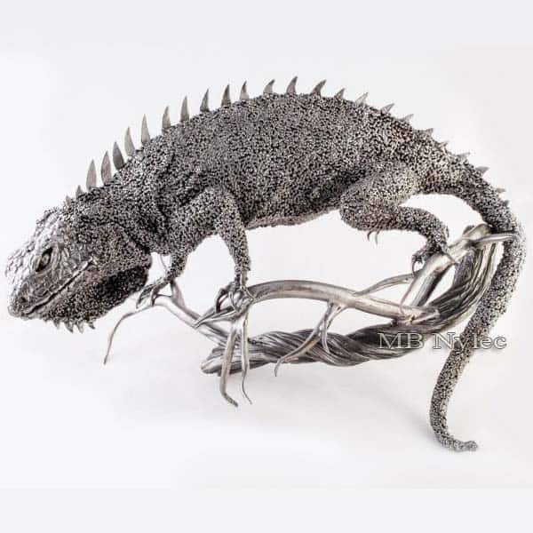 Hand-forged steel iguana with back spikes climbing a twisted steel branch