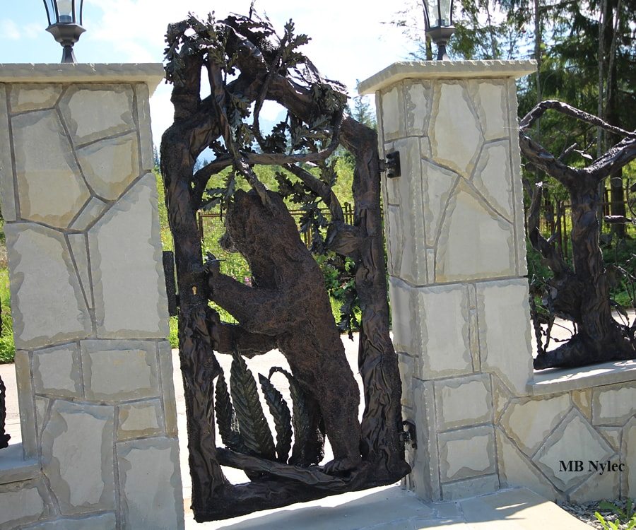 Highland-style wicket gate with a forged bear and arching branches