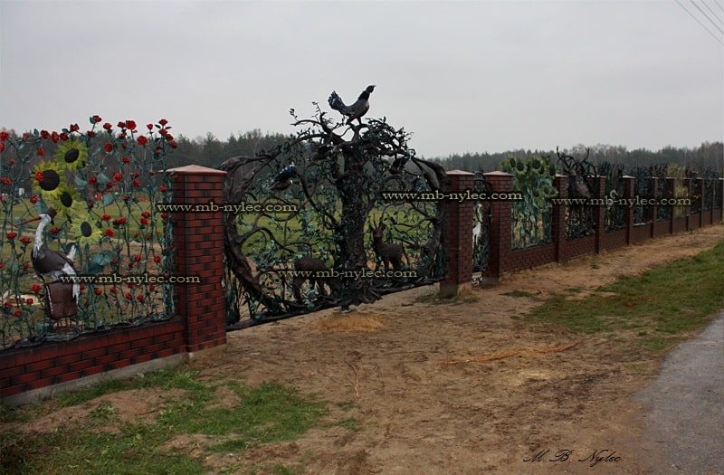 Hunting gate BM25 within a long brick and forged fence beside a field