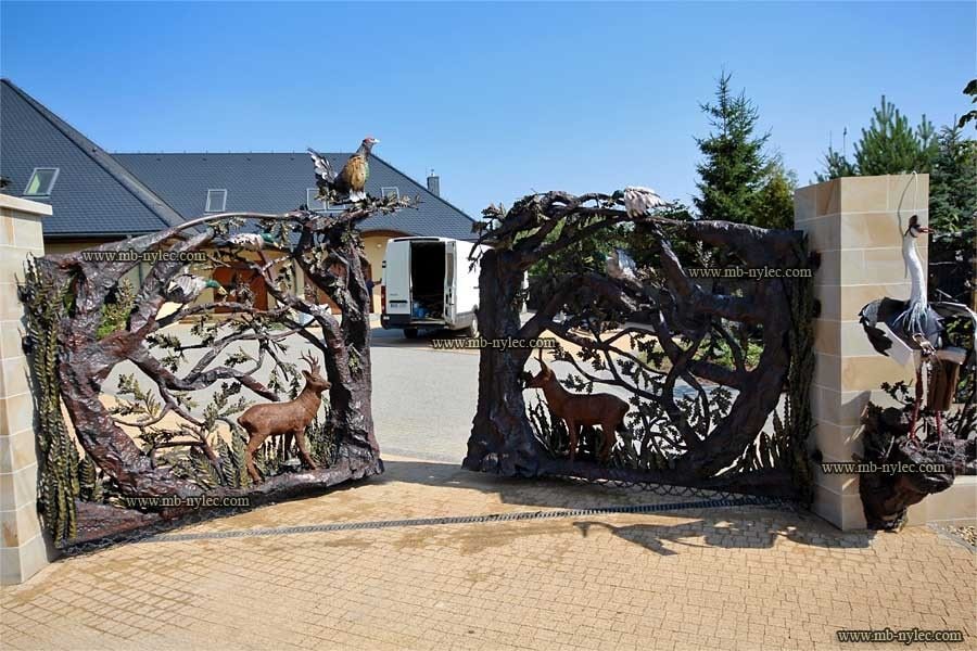 Open driveway gate of the hunting fence BM30 with forged trees and animals