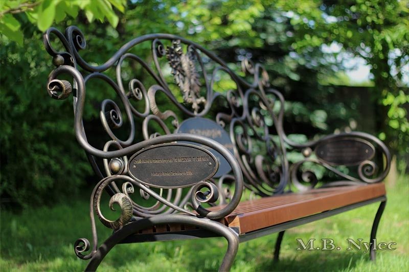 Independence bench MK1C with a forged eagle and plaques, seen at an angle in a garden