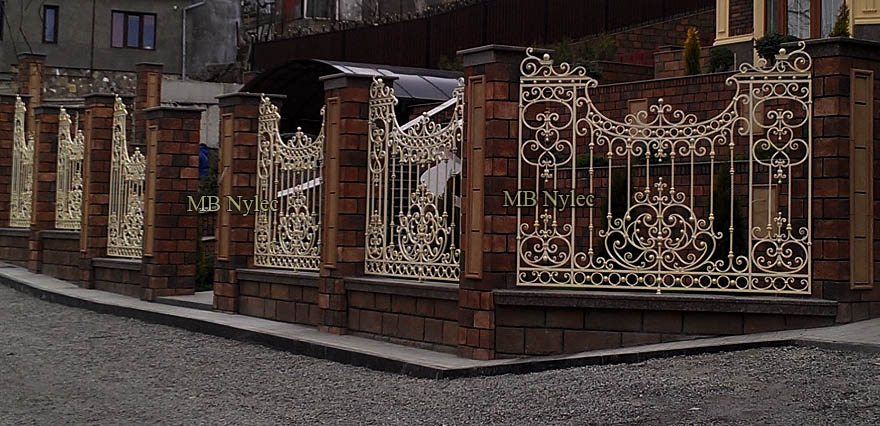Ivory wrought iron fence BP214 between red brick pillars on the corner of a sloping street