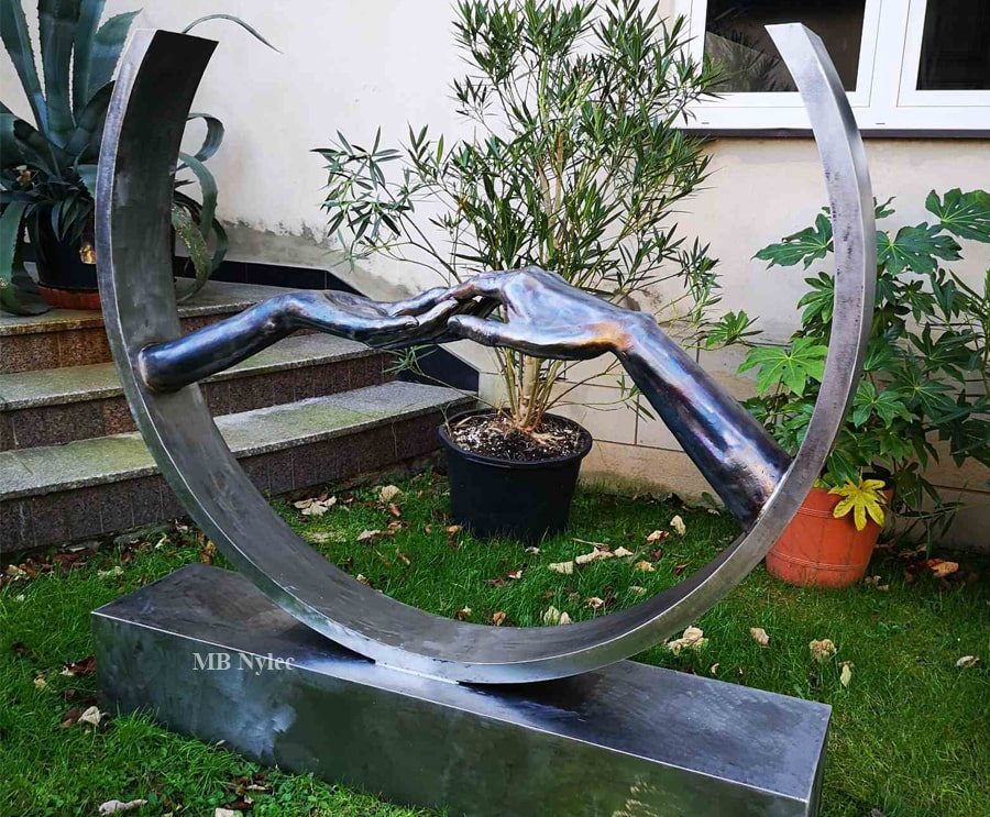 Modern steel sculpture of two hands touching inside a large ring