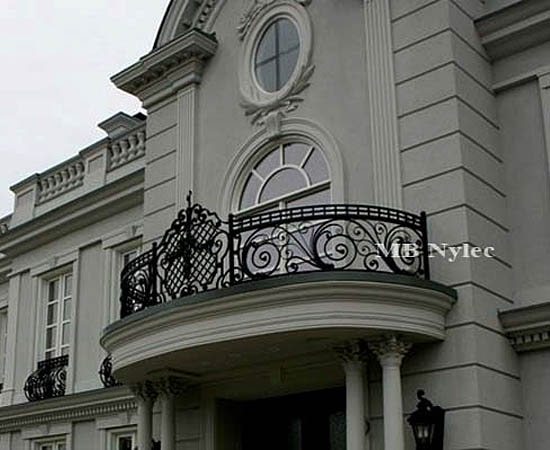 Manor-style railing BA48 with an openwork rosette on a curved balcony above a columned porch