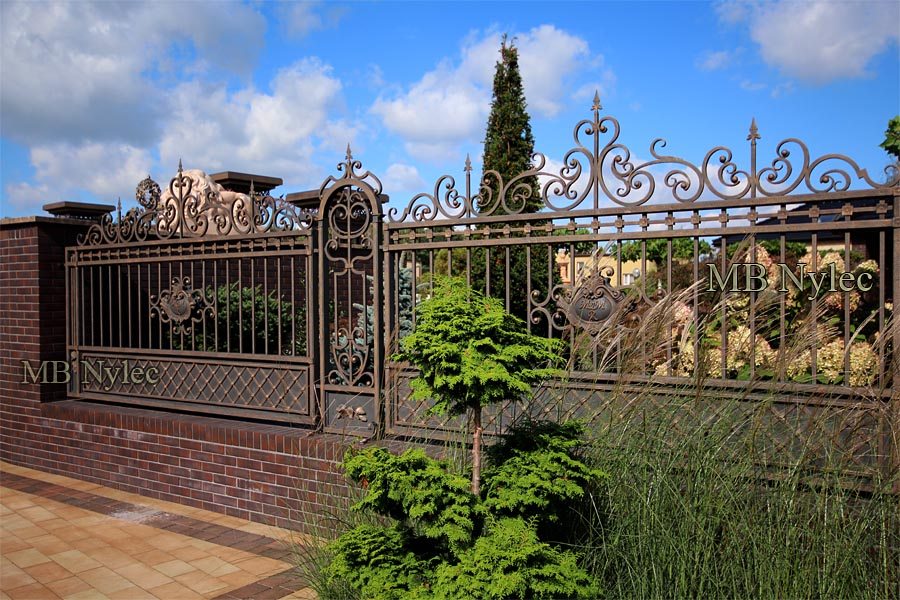 Manor-style forged fence BP54 on a brick plinth with S4 pillars and garden planting