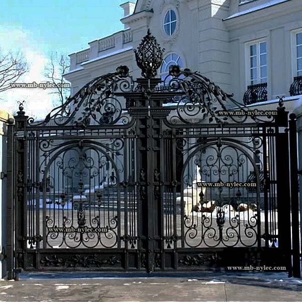 Forged manor gate BP47 and its crown photographed in winter in front of a white residence