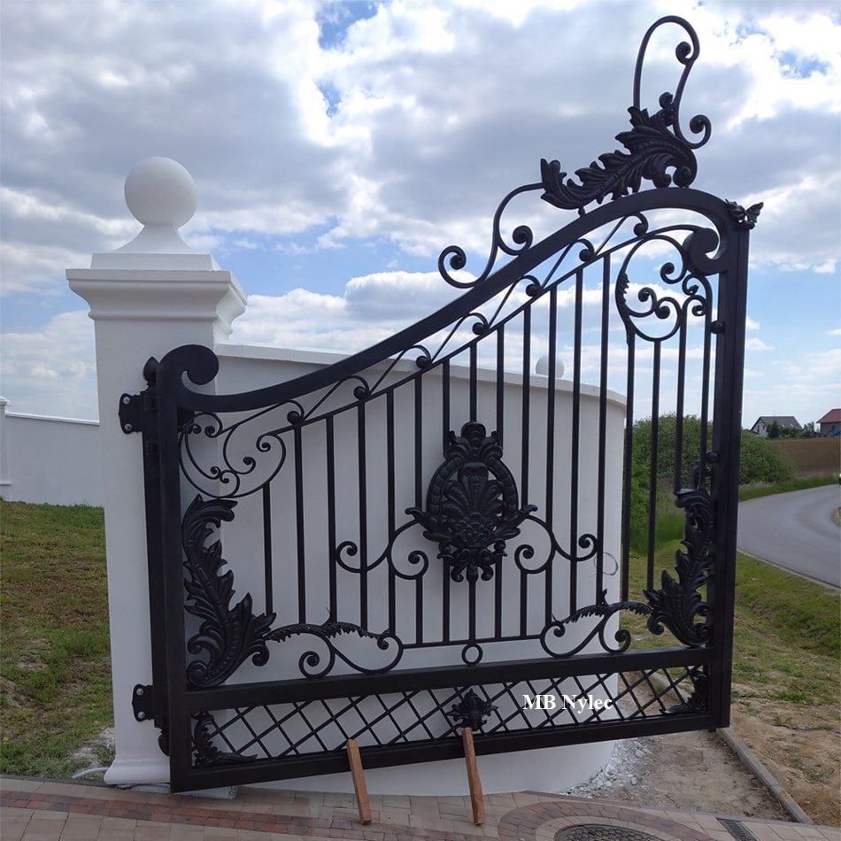 Massive double metal gate between white pillars with finials