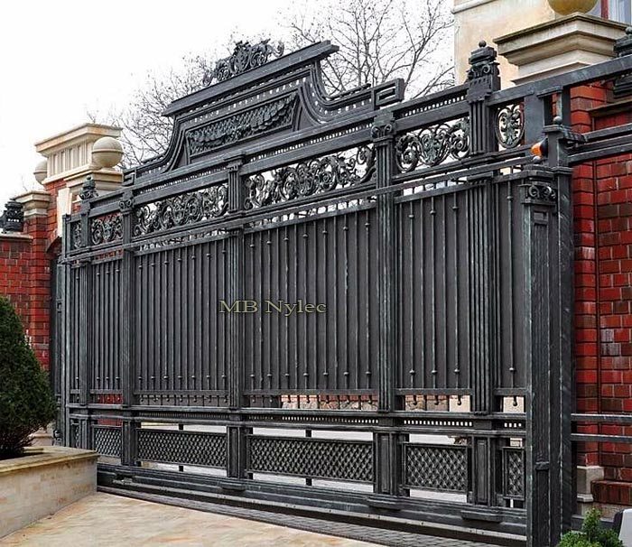 Massive manor gate BP94 with vertical bars and a scrolled crest set in red brick