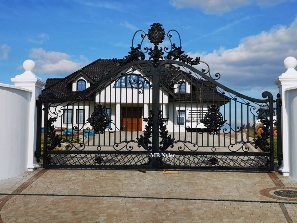 Metal driveway gate with a house visible behind it