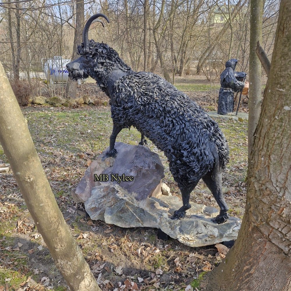 Metal goat garden figure among trees