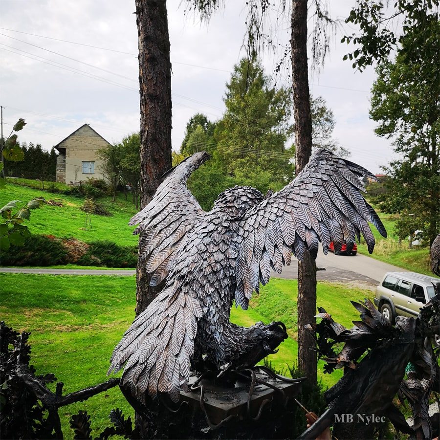 Metal owl sculpture with spread wings on a gate