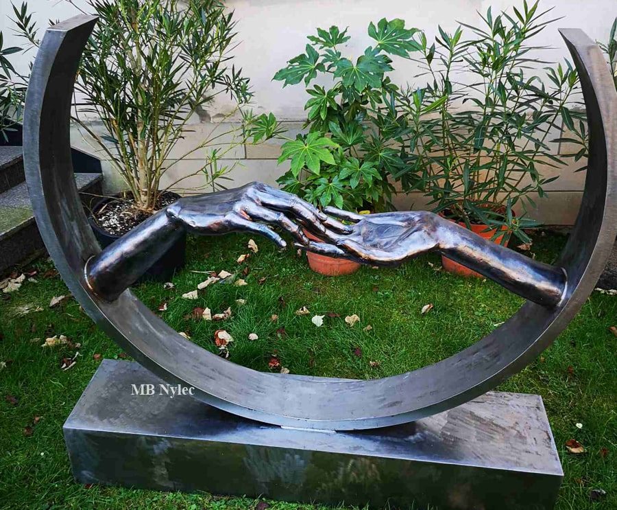 Metal sculpture of a woman's and a man's hands gently touching