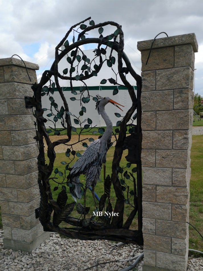 Metal sculpture wicket gate with a heron between block pillars