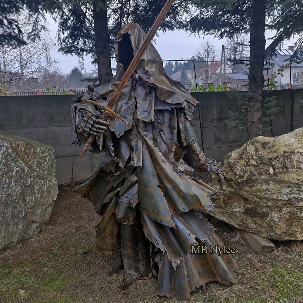 Hooded metal wraith figure striding forward in a garden