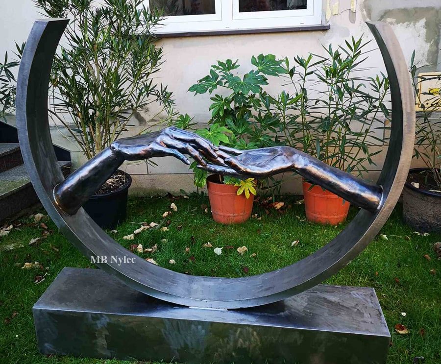 Modern love sculpture with clasped hands in a garden