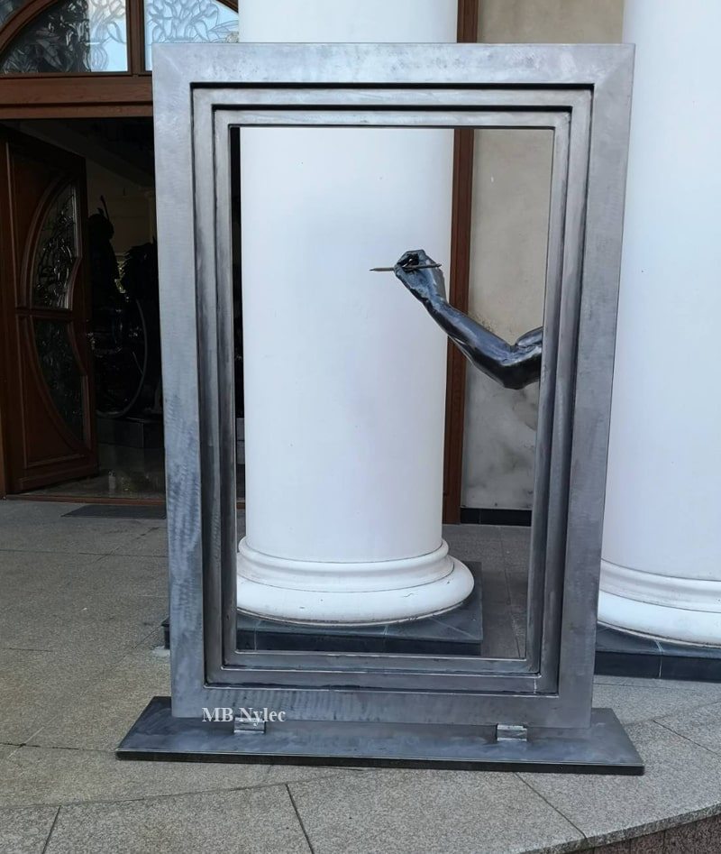 Modern metal frame sculpture with an arm holding a brush