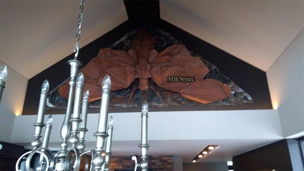 Moth bas-relief Z60 above a chandelier in a tall living space