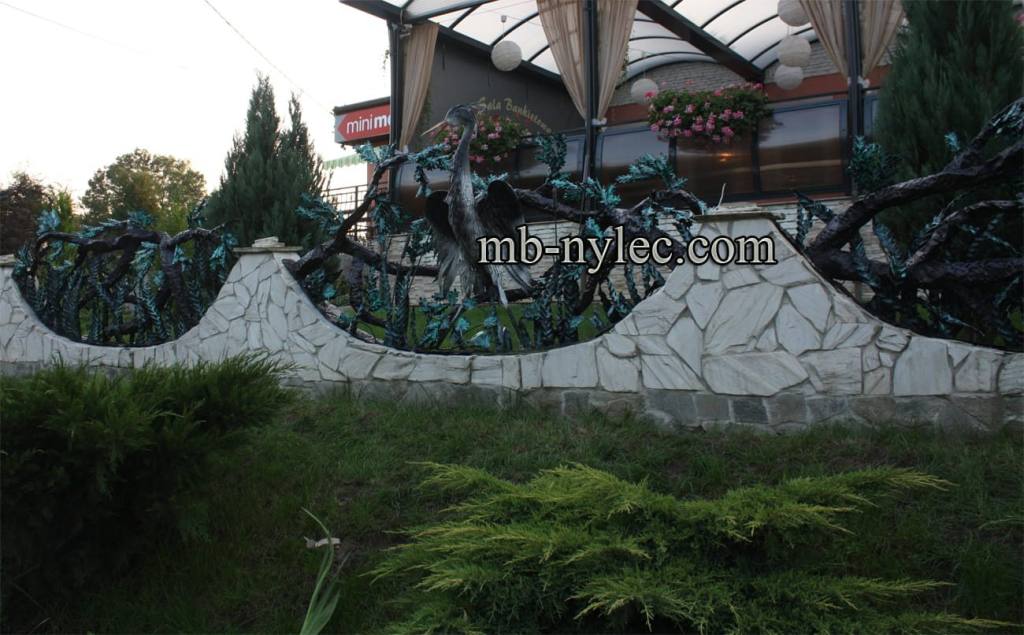 Forged plant fence BM33 with oak branches set into a wavy stone wall