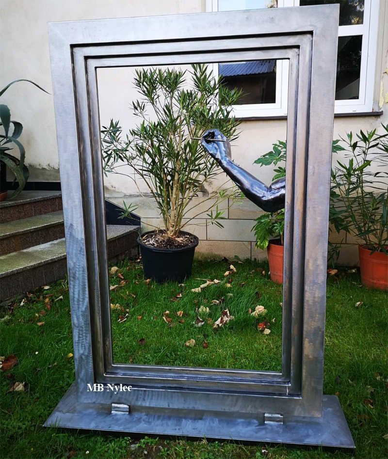 Modern steel sculpture of a hand painting inside an empty frame