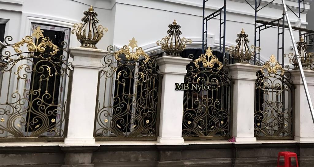 Palace-style forged fence BP269 with gilded crowns on white pillars and scrolled panels