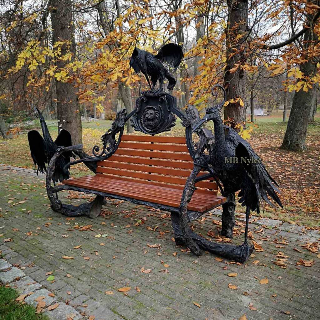 Park bench on forged steel limbs under autumn trees