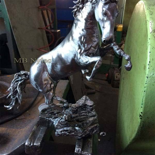 Miniature polished steel stallion rearing on a rugged rock-shaped base