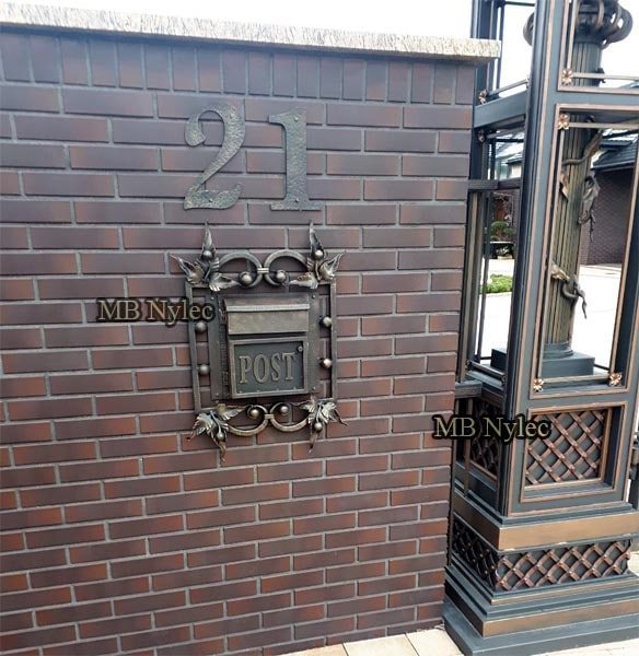 Forged POST mailbox PS2 in a square frame with leaves on a clinker brick wall