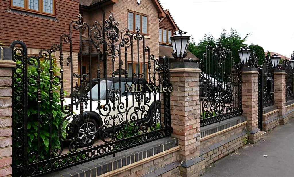 Richly decorated forged fence BP234 with crested panels between brick pillars topped with lanterns
