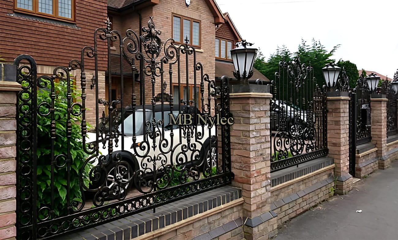 Wrought iron fence on brick pillars topped with lanterns along a street
